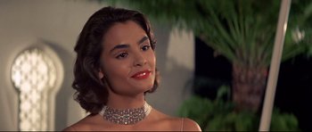Movie still from “Licence to Kill” (1989), directed by John Glen – A woman wearing a diamond necklace and a red lipstick; Close Up shot, Low angle