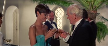 Movie still from “Licence to Kill” (1989), directed by John Glen – A man and a woman are holding wine glasses; Medium shot, Low angle
