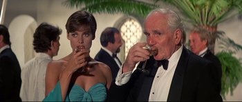 Movie still from “Licence to Kill” (1989), directed by John Glen – A man and a woman are drinking wine; Medium shot, Low angle