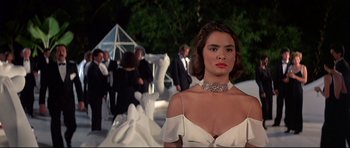 Movie still from “Licence to Kill” (1989), directed by John Glen – A woman in a white dress standing in front of a crowd; Close Up shot, Low angle