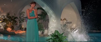Movie still from “Licence to Kill” (1989), directed by John Glen – A woman in a blue dress standing in front of a fountain; Wide shot, Low angle