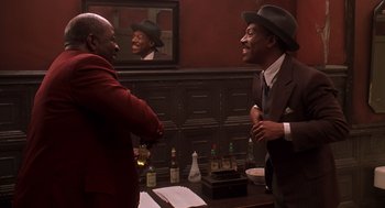 Movie still from “Life” (1999), directed by Ted Demme – Two men are shaking hands in front of a painting; Medium shot, Over the shoulder angle