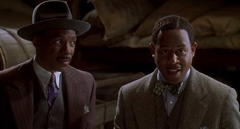 Movie still from “Life” (1999), directed by Ted Demme – A couple of men standing next to each other in a room; Close Up shot, Over the shoulder angle