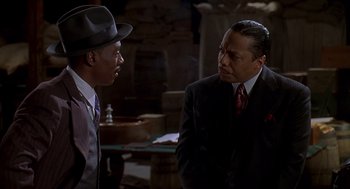 Movie still from “Life” (1999), directed by Ted Demme – A man in a suit and a hat talking to another man in a suit and a hat; Medium shot, Over the shoulder angle