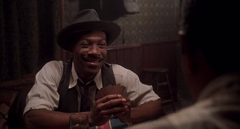 Movie still from “Life” (1999), directed by Ted Demme – A man sitting at a table holding a piece of chocolate; Close Up shot, Over the shoulder angle