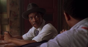 Movie still from “Life” (1999), directed by Ted Demme – A man wearing a hat sitting next to another man; Close Up shot, Over the shoulder angle