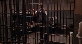 Movie still from “Life” (1999), directed by Ted Demme – A man standing in a jail cell with his hands on the bars; Wide shot, High angle