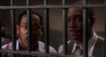 Movie still from “Life” (1999), directed by Ted Demme – A couple of men standing next to each other behind bars; Close Up shot, Low angle