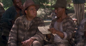 Movie still from “Life” (1999), directed by Ted Demme – A couple of men sitting next to each other on the ground; Medium shot, Over the shoulder angle