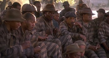 Movie still from “Life” (1999), directed by Ted Demme – A group of men sitting next to each other in prison uniforms; Medium shot, High angle
