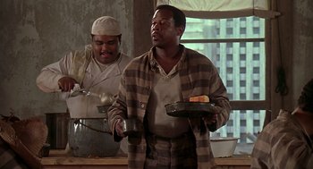 Movie still from “Life” (1999), directed by Ted Demme – A man holding a tray of food in front of another man; Medium shot, Low angle
