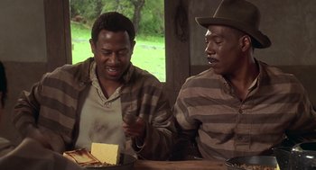 Movie still from “Life” (1999), directed by Ted Demme – Two men sitting at a table with a sandwich in front of them; Medium shot, High angle