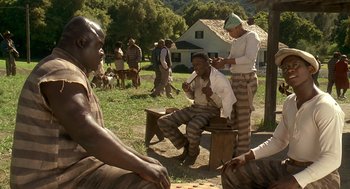 Movie still from “Life” (1999), directed by Ted Demme – A group of men in prison uniforms sitting in a field; Medium shot, High angle