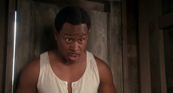 Movie still from “Life” (1999), directed by Ted Demme – A man in a white shirt is looking at the camera; Close Up shot, High angle