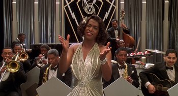 Movie still from “Life” (1999), directed by Ted Demme – A woman in a silver dress is singing in front of an orchestra; Medium shot, Low angle