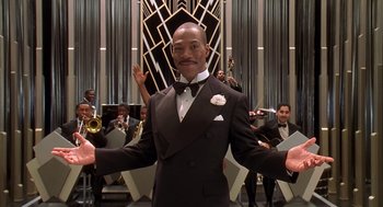 Movie still from “Life” (1999), directed by Ted Demme – A man in a suit and tie holding his hands out; Medium shot, Low angle