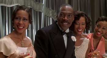 Movie still from “Life” (1999), directed by Ted Demme – A man in a tuxedo standing next to two women in formal wear; Close Up shot, Over the shoulder angle