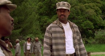 Movie still from “Life” (1999), directed by Ted Demme – A man in prison clothing standing in front of two other men; Medium shot, Low angle