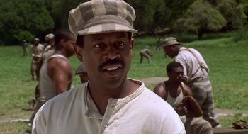 Movie still from “Life” (1999), directed by Ted Demme – A man with a hat is standing in front of a group of men; Close Up shot, Low angle