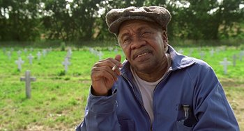 Movie still from “Life” (1999), directed by Ted Demme – An older man wearing a hat is sitting in the grass; Close Up shot, Low angle