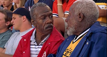 Movie still from “Life” (1999), directed by Ted Demme – Two older men talking to each other in front of a group of people; Close Up shot, High angle