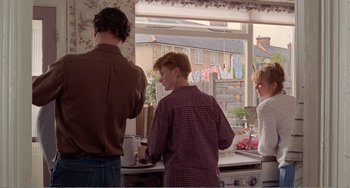 Movie still from “Life Is Sweet” (1990), directed by Mike Leigh – A group of people standing around a kitchen sink; Medium shot, Low angle