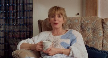 Movie still from “Life Is Sweet” (1990), directed by Mike Leigh – A woman sitting on a chair holding a mug; Medium shot, High angle