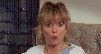 Movie still from “Life Is Sweet” (1990), directed by Mike Leigh – A person sitting in a chair; Close Up shot, Over the shoulder angle