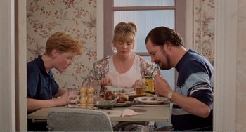 Movie still from “Life Is Sweet” (1990), directed by Mike Leigh – Three people sitting at a table with plates of food on it; Medium shot, High angle