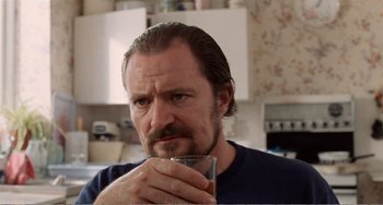 Movie still from “Life Is Sweet” (1990), directed by Mike Leigh – A person holding a glass of beer; Close Up shot, Low angle