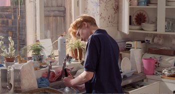 Movie still from “Life Is Sweet” (1990), directed by Mike Leigh – A man is washing dishes in the kitchen sink; Medium shot, High angle