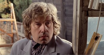 Movie still from “Life Is Sweet” (1990), directed by Mike Leigh – A person wearing a suit and tie; Close Up shot, Over the shoulder angle