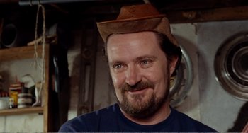 Movie still from “Life Is Sweet” (1990), directed by Mike Leigh – A man with a beard wearing a brown hat; Close Up shot, Over the shoulder angle