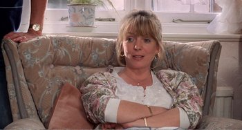 Movie still from “Life Is Sweet” (1990), directed by Mike Leigh – A woman sitting on a couch with her arms crossed; Close Up shot, Over the shoulder angle