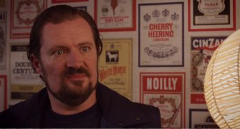 Movie still from “Life Is Sweet” (1990), directed by Mike Leigh – A person in front of a bunch of posters on a wall; Close Up shot, Over the shoulder angle