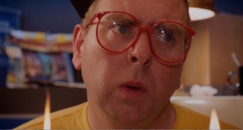 Movie still from “Life Is Sweet” (1990), directed by Mike Leigh – A person wearing glasses and a hat; Close Up shot, Low angle