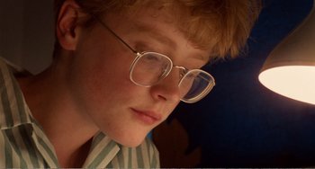 Movie still from “Life Is Sweet” (1990), directed by Mike Leigh – A person wearing glasses and a striped shirt; Close Up shot, Low angle