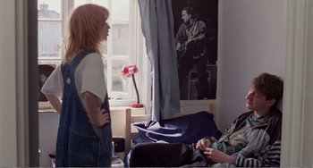 Movie still from “Life Is Sweet” (1990), directed by Mike Leigh – A woman standing next to another woman in a room; Wide shot, Over the shoulder angle