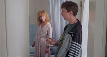 Movie still from “Life Is Sweet” (1990), directed by Mike Leigh – A man and a woman standing next to each other in front of a bathroom door; Medium shot, Over the shoulder angle