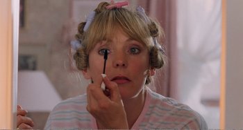 A woman putting makeup on her face in front of a mirror