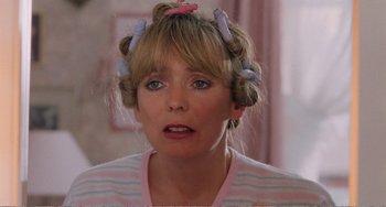 Movie still from “Life Is Sweet” (1990), directed by Mike Leigh – A person with curlers in their hair; Close Up shot, Over the shoulder angle