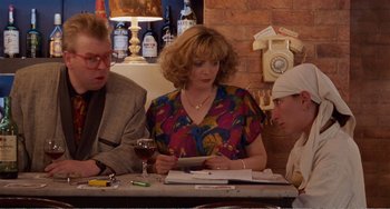 Movie still from “Life Is Sweet” (1990), directed by Mike Leigh – Three people sitting at a table with a glass of red wine; Medium shot, Over the shoulder angle
