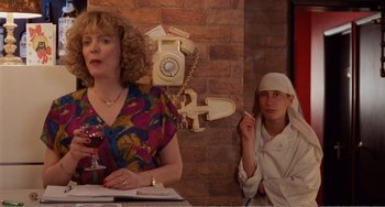 Movie still from “Life Is Sweet” (1990), directed by Mike Leigh – A woman standing next to a man holding a cigarette; Medium shot, Over the shoulder angle