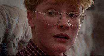 Movie still from “Life Is Sweet” (1990), directed by Mike Leigh – A person wearing glasses and a plaid shirt; Close Up shot, Over the shoulder angle