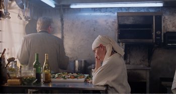 Movie still from “Life Is Sweet” (1990), directed by Mike Leigh – A man sitting at a table in front of a tray of food; Medium shot, Over the shoulder angle