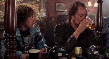 Movie still from “Life Is Sweet” (1990), directed by Mike Leigh – Two men sitting at a table drinking beer; Medium shot, Over the shoulder angle