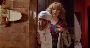 Movie still from “Life Is Sweet” (1990), directed by Mike Leigh – A man and a woman standing next to each other in a doorway; Medium shot, Over the shoulder angle