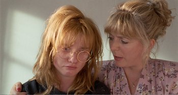 Movie still from “Life Is Sweet” (1990), directed by Mike Leigh – A woman and a woman wearing glasses looking at each other; Close Up shot, Over the shoulder angle