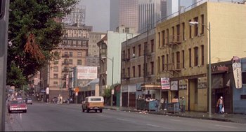 Movie still from “Life Stinks” (1991), directed by Mel Brooks – A street scene with a car driving down the road; Extreme Wide shot, High angle