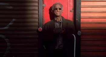 Movie still from “Life Stinks” (1991), directed by Mel Brooks – An older man standing in front of a red door; Medium shot, Low angle